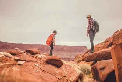 kid and dad in the desert; both wearing backpacks with outdoor gear for kids