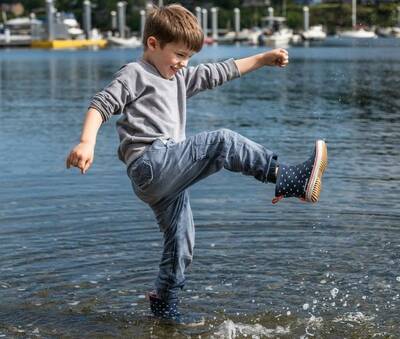 Child splashing in Grundéns New Guppy Rain Boots