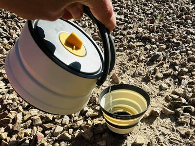 pouring hot water into a collapsible camp cup from sea to summit's frontier line.