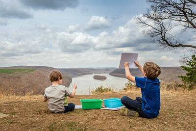 kids playing with the outdoor gear in their box next to a lake